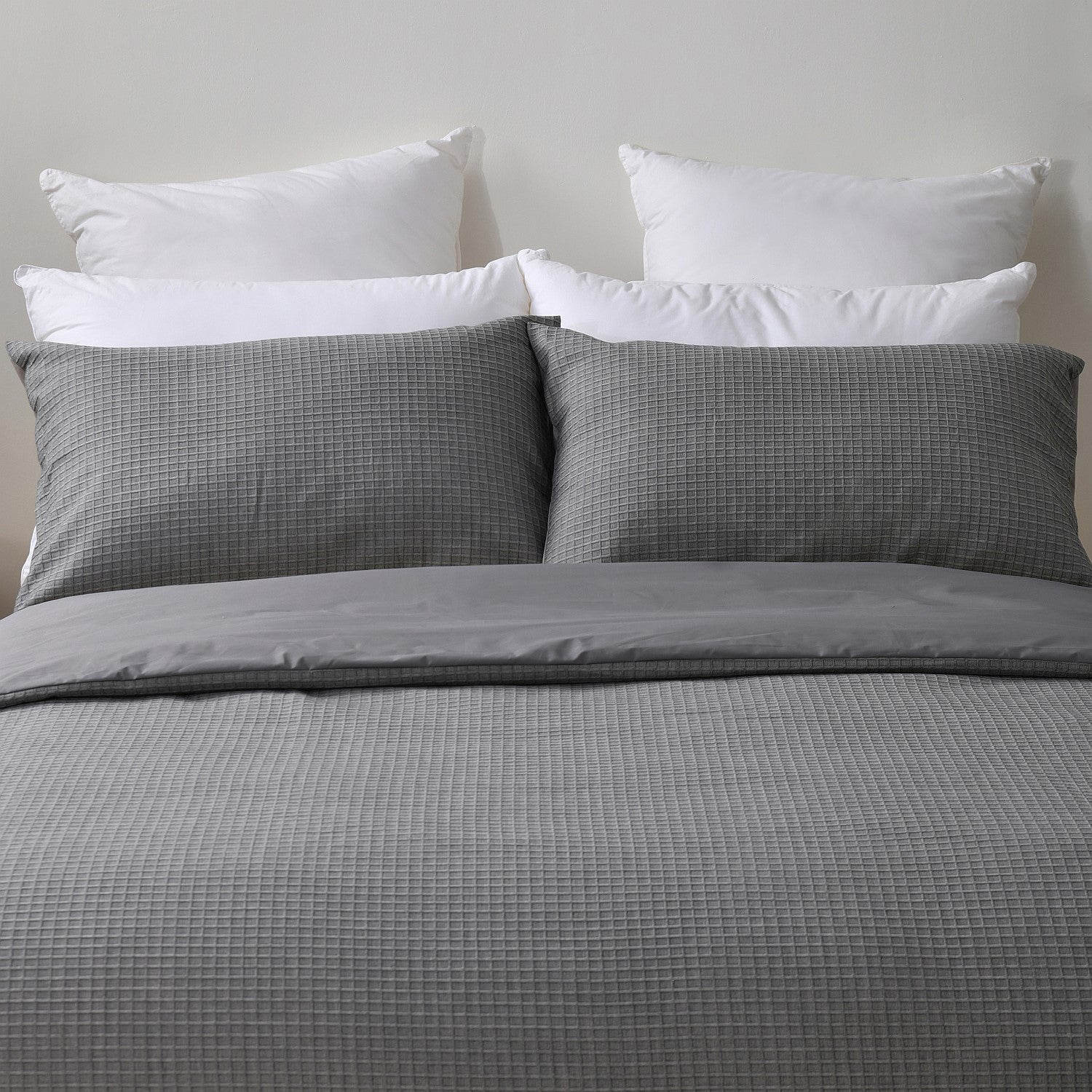 Gray checkered bedding set with white pillows on a neutral background