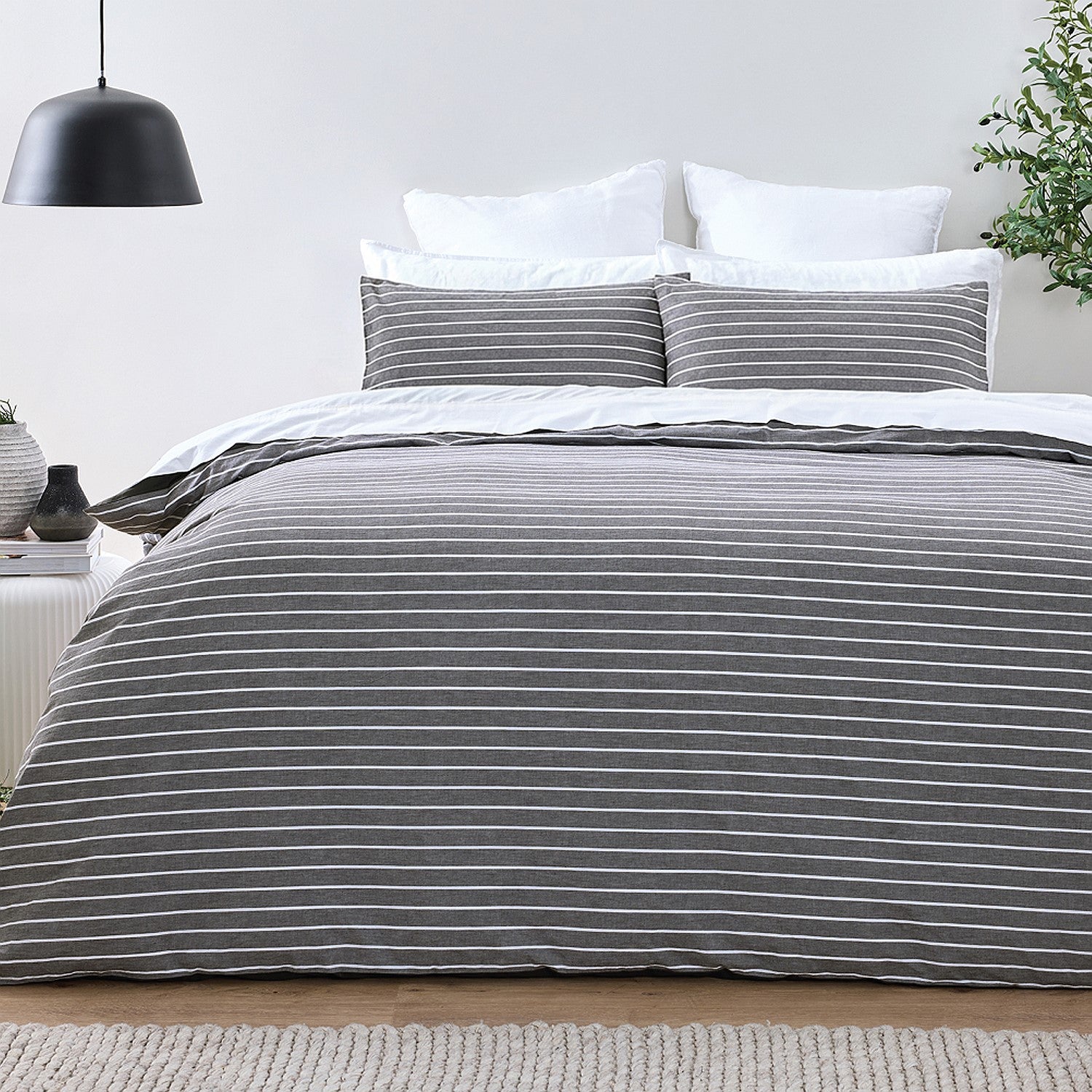 Bed with gray striped bedding in a minimalistic bedroom setting.