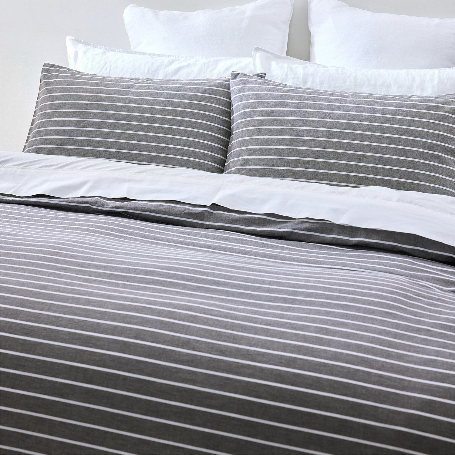 Gray and white striped bedding set with pillows on a bed.