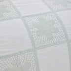 Close-up of a quilt with geometric pattern on light gray fabric