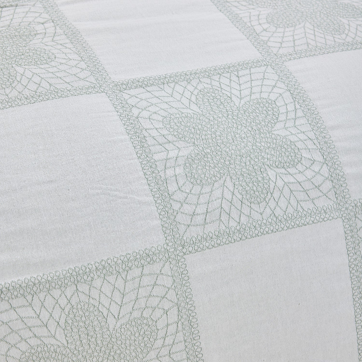 Close-up of a quilt with geometric pattern on light gray fabric