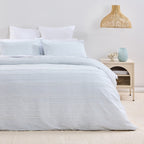 Neatly made bed with light blue bedding in a bedroom setting.