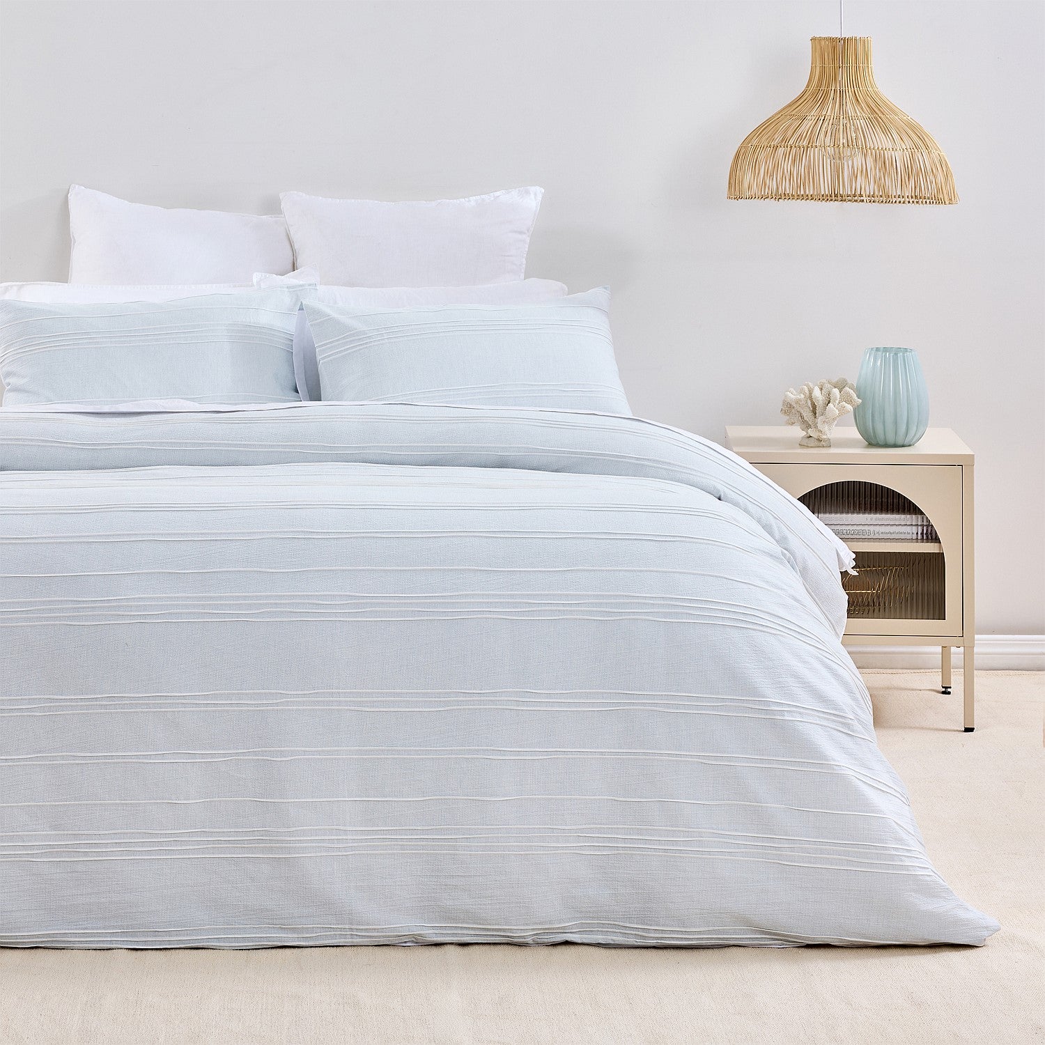 Neatly made bed with light blue bedding in a bedroom setting.