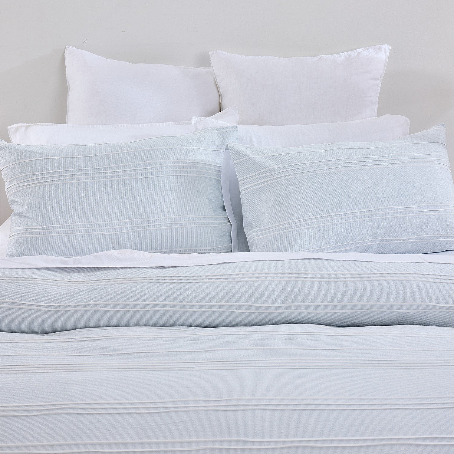 Light blue striped bedding set with white pillows on a neutral background