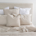 Neatly arranged pillows on a bed with a neutral color scheme.