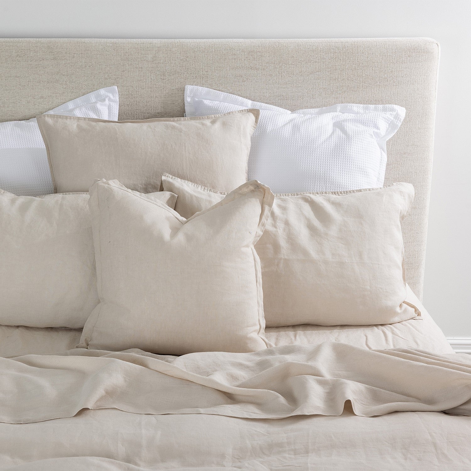 Neatly arranged pillows on a bed with a neutral color scheme.