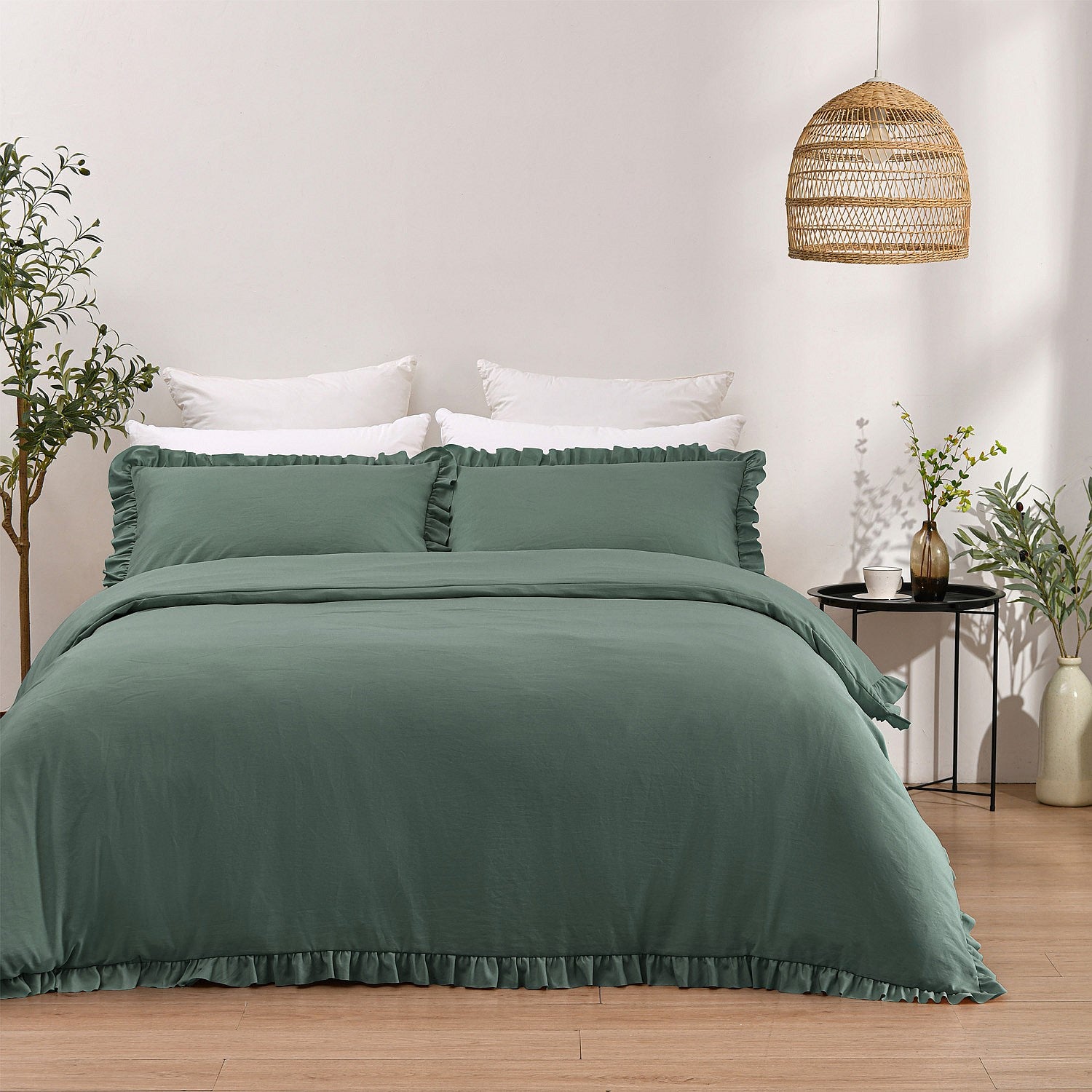 Green bedding set on a bed in a bedroom with a wicker lamp and plants.