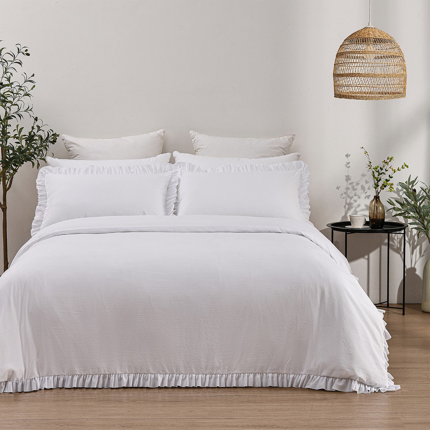 White bedding set on a bed in a bedroom with plants and a woven pendant light.
