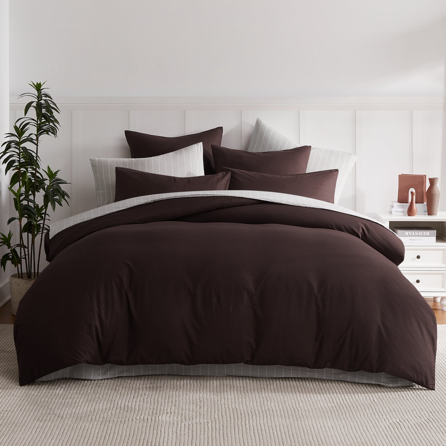 A beautifully styled bed dressed in rich hazelnut bedding is layered with crisp white pinstripe accents for a warm, sophisticated contemporary bedroom look.