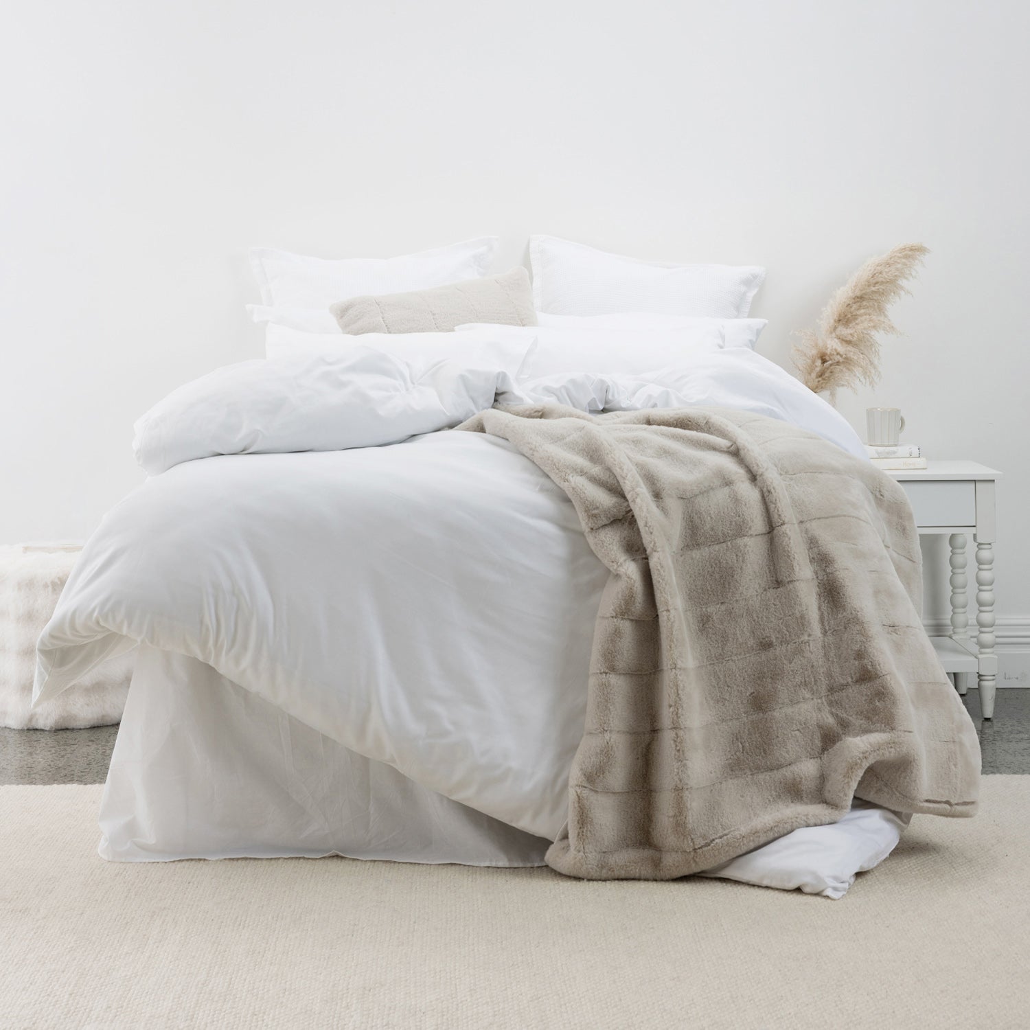 White lyocell and cotton duvet cover set styled with layered white bedding and a soft neutral throw in a bright, minimalist bedroom setting.