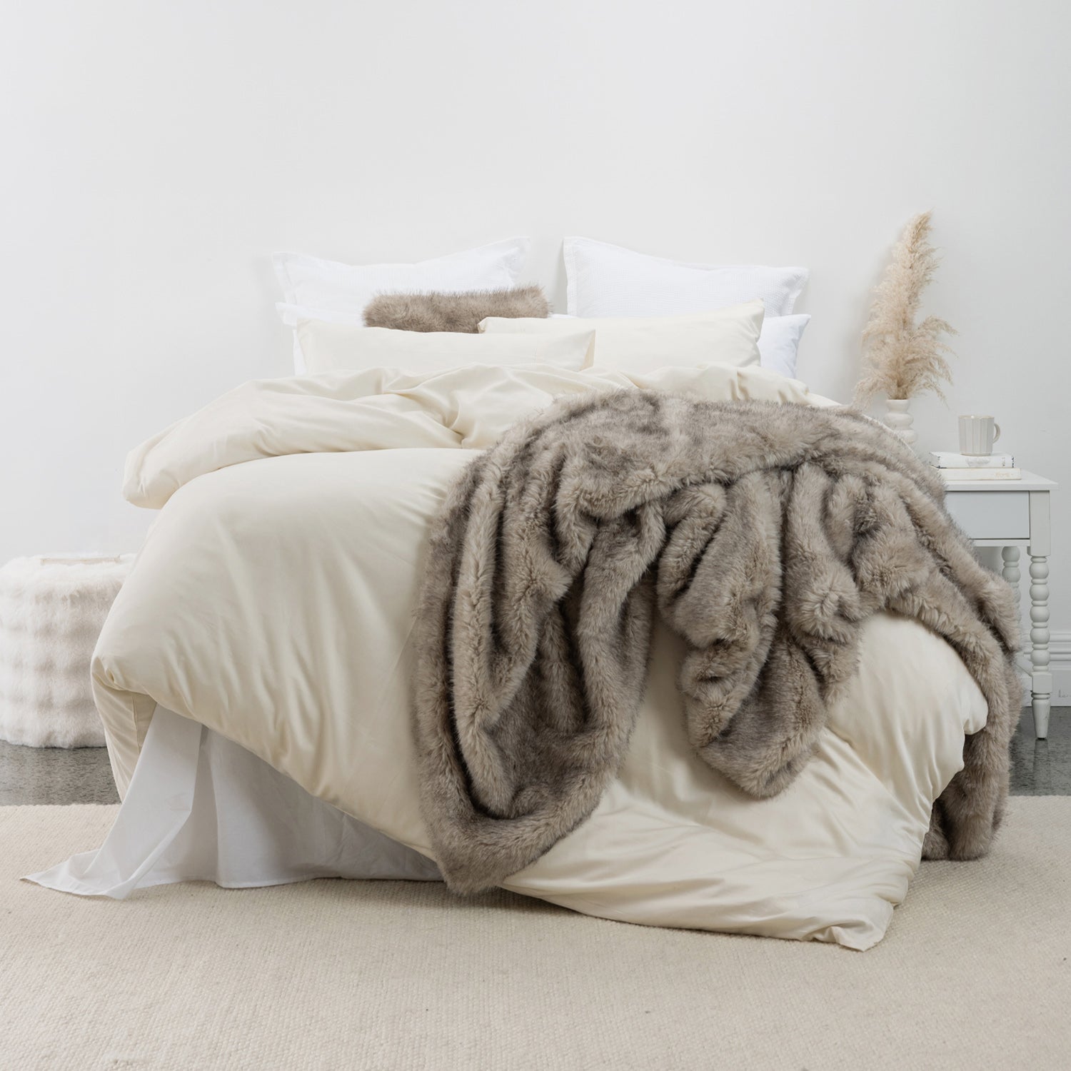 Yellow lyocell and cotton duvet cover set styled with layered neutral cushions and a taupe faux fur throw in a calm, contemporary bedroom setting.