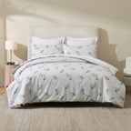 A beautifully styled bed dressed in soft white bedding with delicate blue floral sprigs creates a fresh, airy bedroom with timeless cottage-inspired charm.
