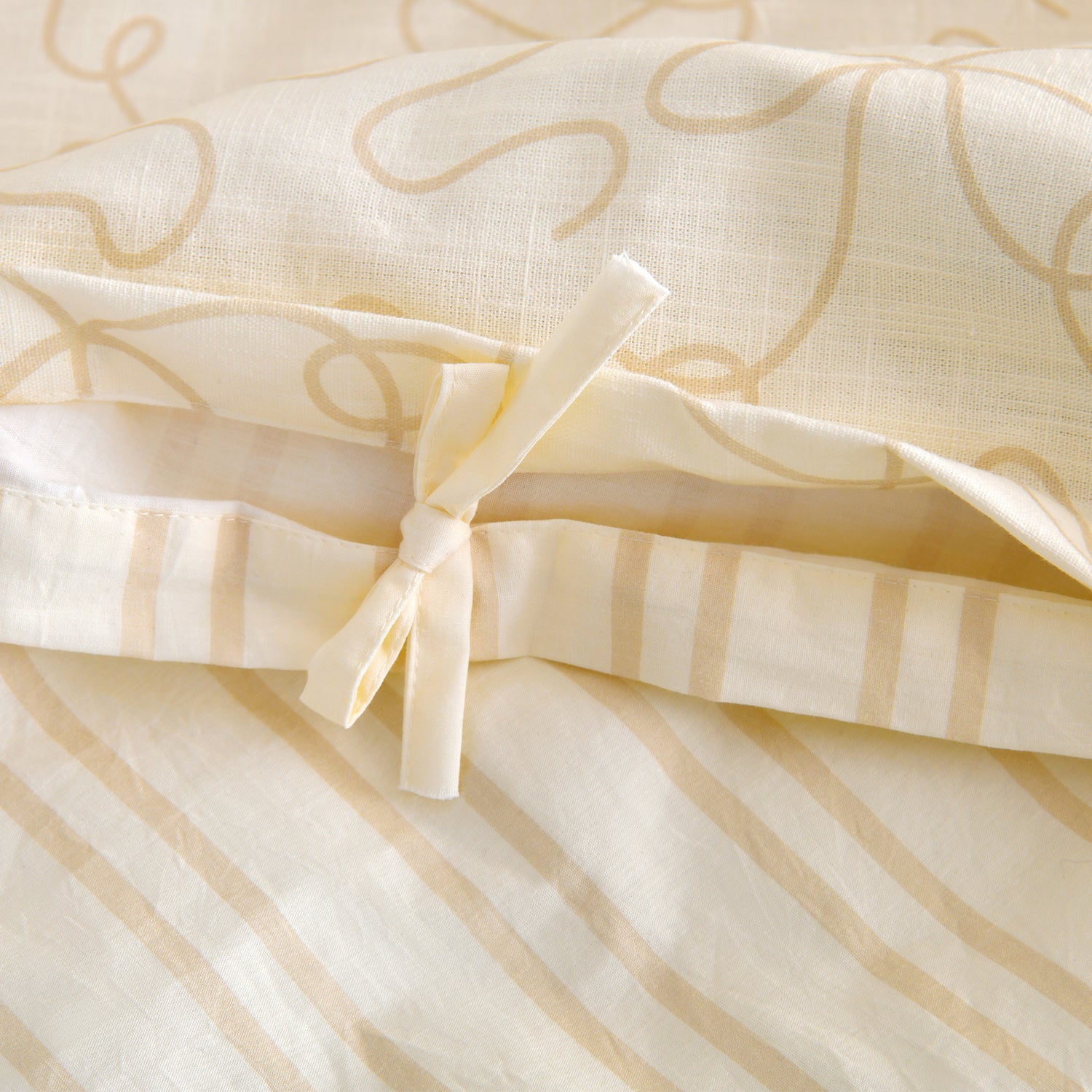Close-up of the external bow tie closure and reversible striped reverse on the lemon and cream cotton duvet cover set.