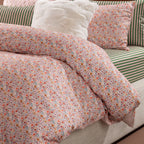 Close-up of Marlo Mia Floral duvet cover set featuring a delicate multicoloured floral print with coordinating green and pink striped bedding.