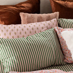 Close-up of Marlo Mia Stripe pillowcases styled with coordinating blush and rust-toned cushions.