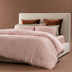 Marlo Mia Duvet Cover Set styled on a bed featuring a blush botanical print, blush reverse, green striped accents, and coordinating decorative cushions.
