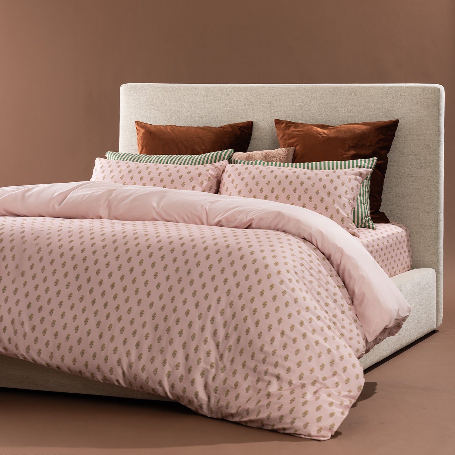 Marlo Mia Duvet Cover Set styled on a bed featuring a blush botanical print, blush reverse, green striped accents, and coordinating decorative cushions.
