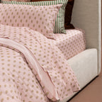 Detailed view of the Marlo Mia duvet cover and fitted sheet showcasing the blush botanical print and coordinating green striped bedding.