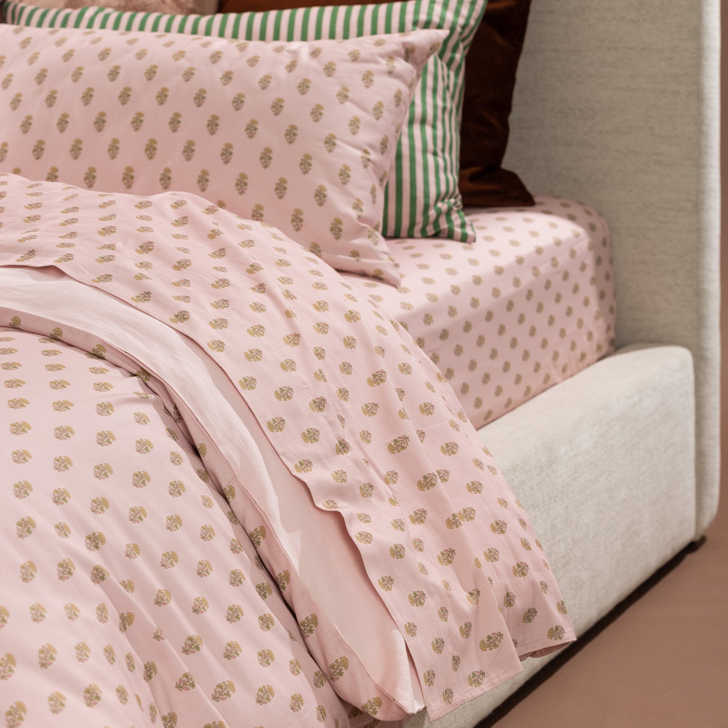 Detailed view of the Marlo Mia duvet cover and fitted sheet showcasing the blush botanical print and coordinating green striped bedding.
