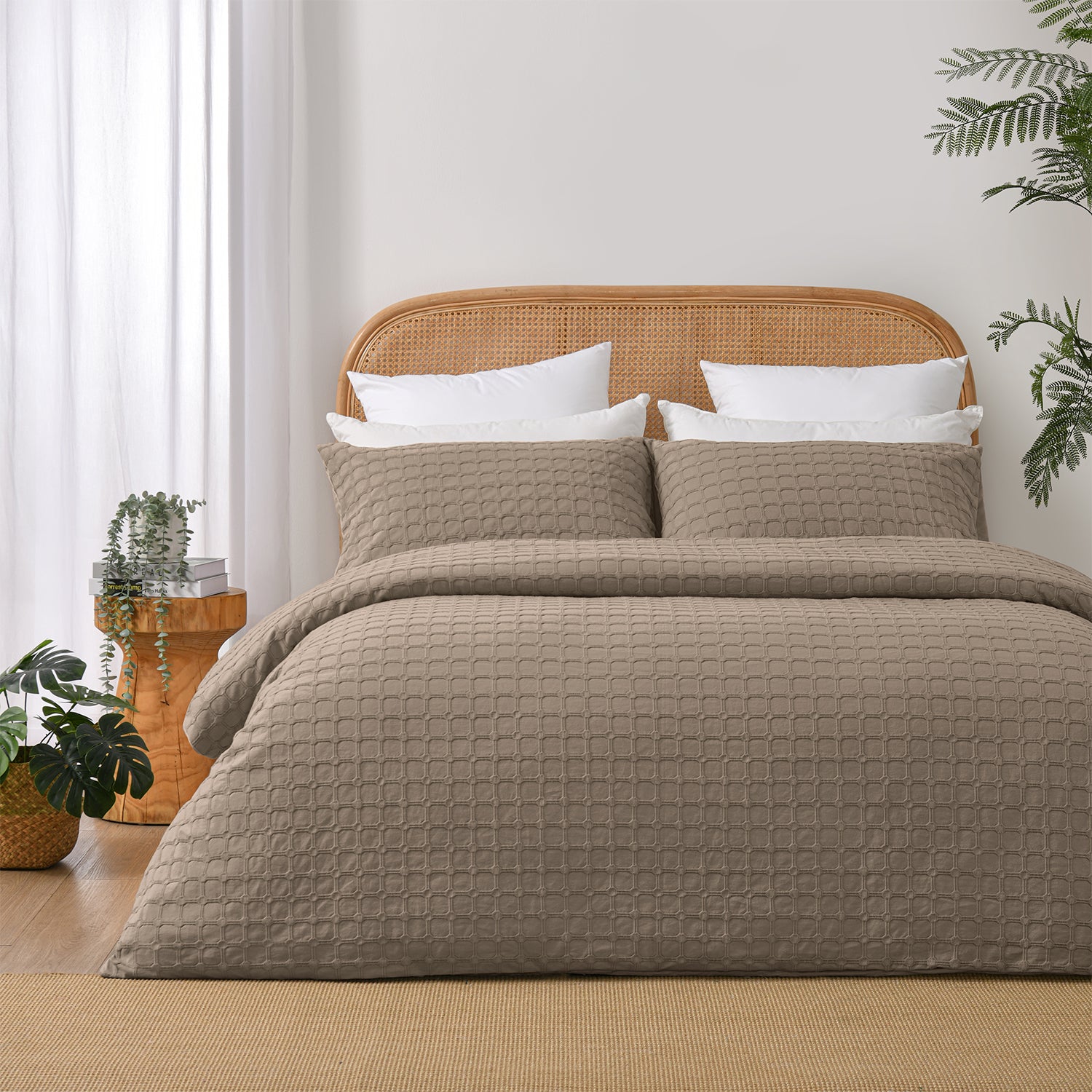Fieldcrest Maison cotton duvet cover set in mocha with a textured geometric pattern styled on a bed with a rattan headboard and timber bedside table.