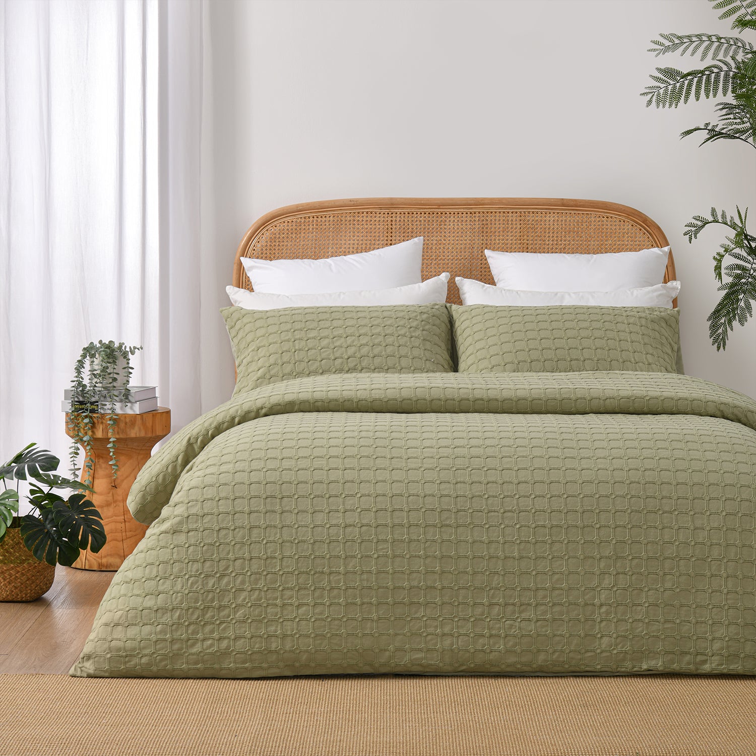 Fieldcrest Maison cotton duvet cover set in olive with a textured geometric pattern styled on a bed with a rattan headboard and timber bedside table.
