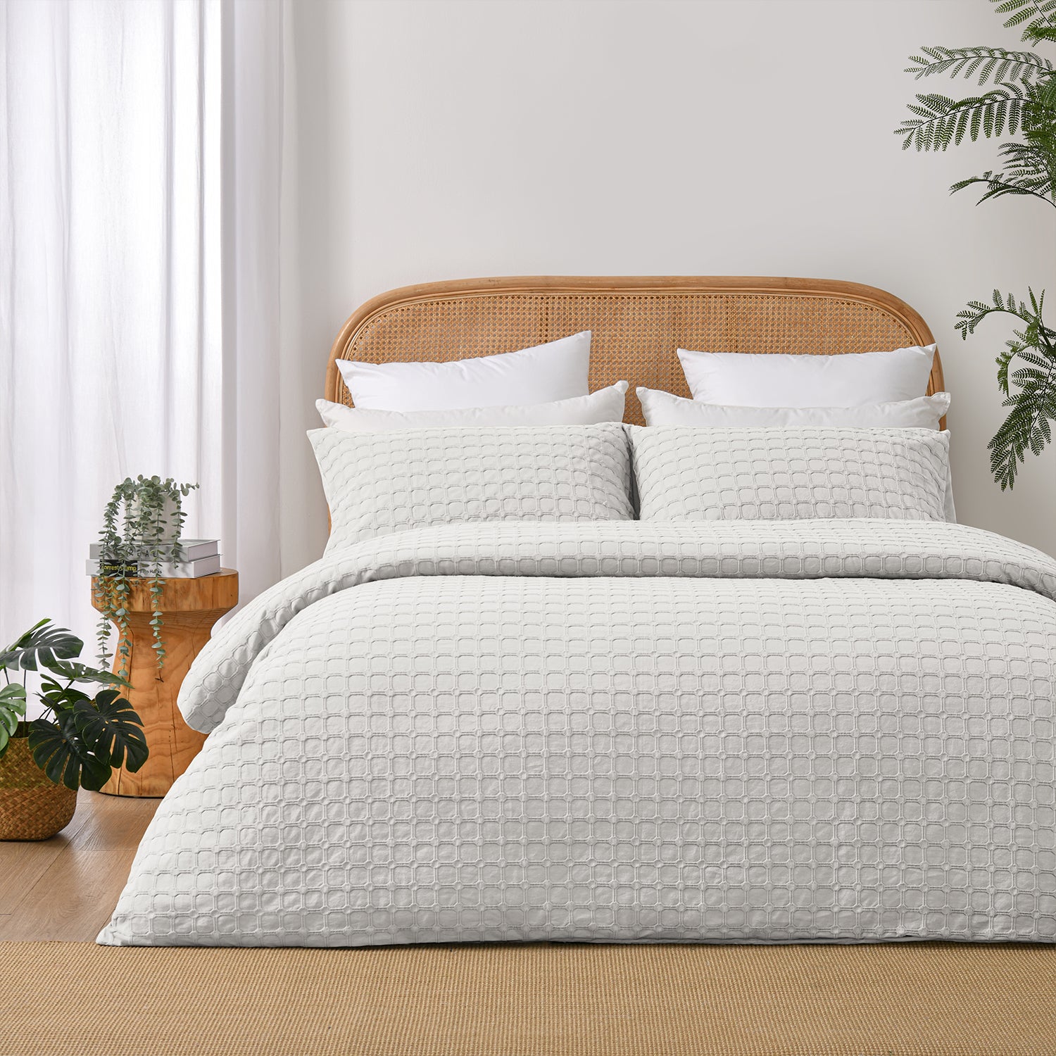 Fieldcrest Maison cotton duvet cover set in white with a textured geometric pattern styled on a bed with a rattan headboard and timber bedside table.