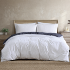 White striped bedding set on a bed with wooden headboard and nightstands.
