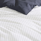 Close-up of striped bedding with a navy pillow