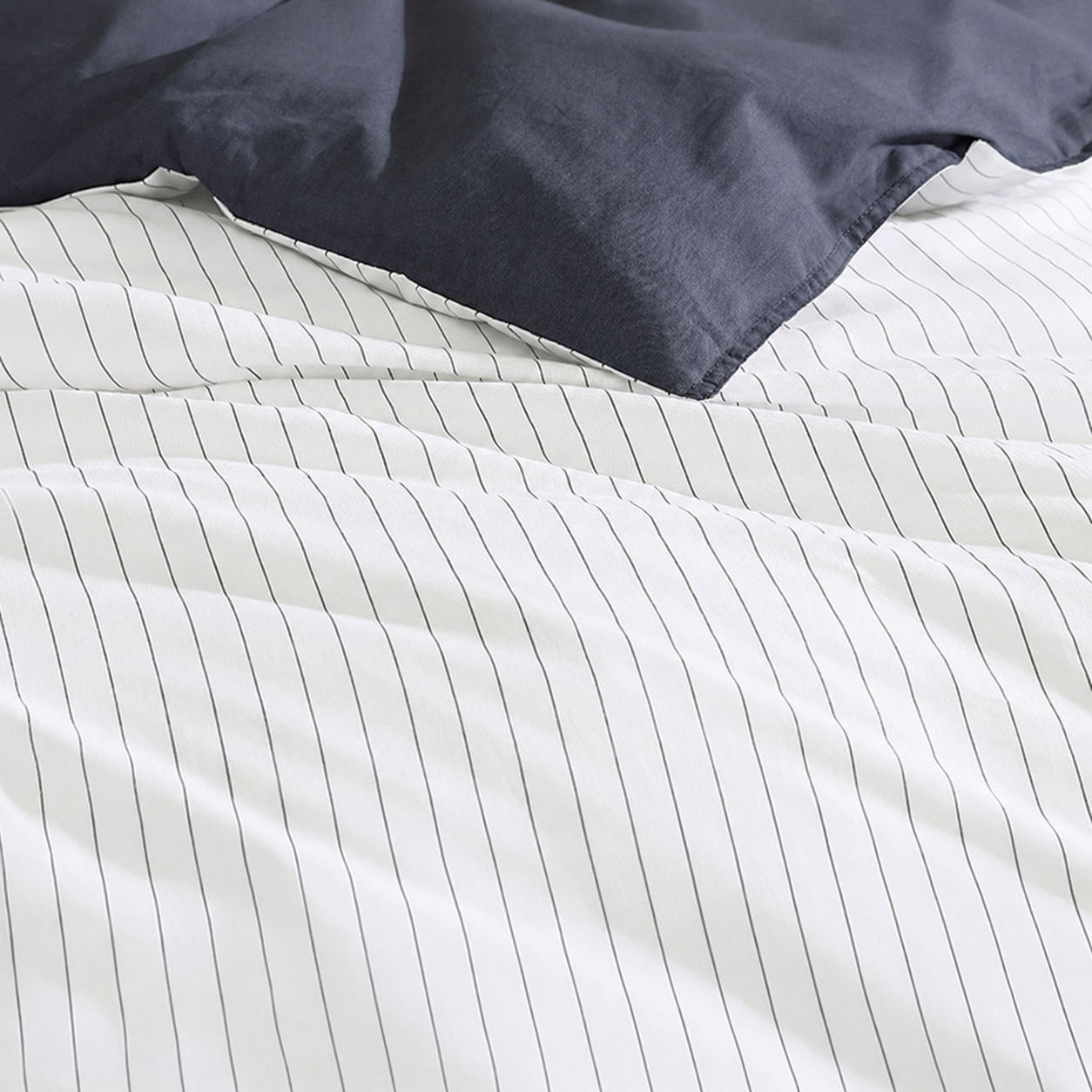 Close-up of striped bedding with a navy pillow