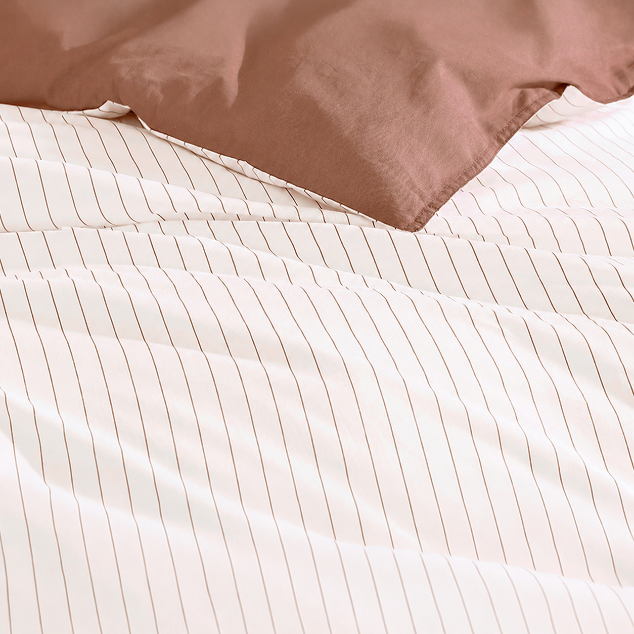 Close-up of a brown pillow and white striped bedding