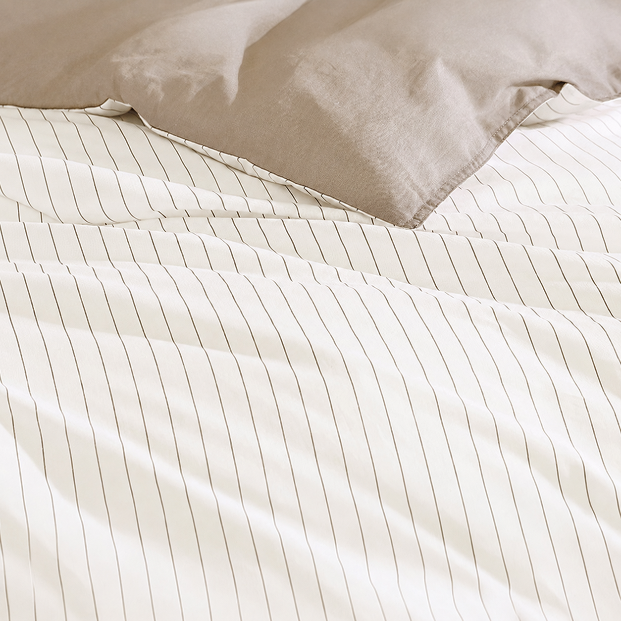 Close-up of beige striped bedding with a pillow.