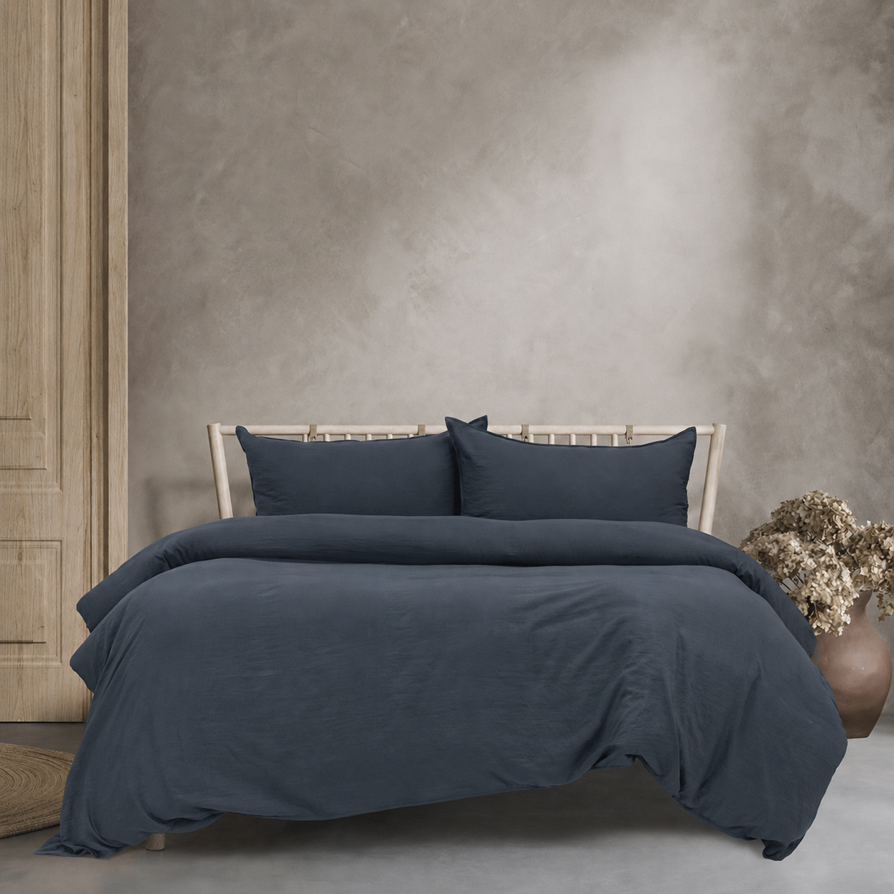 Dark blue bedding set on a bed against a textured wall.