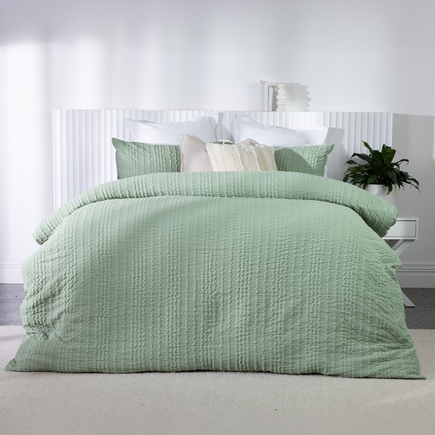Soft sage textured duvet cover set styled on a bed with matching pillowcases and neutral accent cushions in a bright contemporary bedroom.
