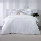 White textured duvet cover set styled on a bed with matching pillowcases and neutral accent cushions in a bright contemporary bedroom.