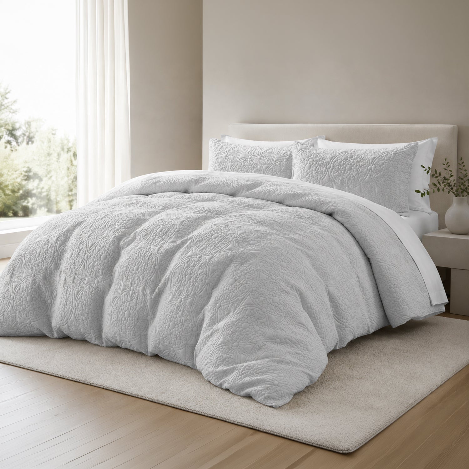 A plush grey textured bedding set, including a fluffy duvet cover and two matching pillows, styled on a bed in a modern, minimalist bedroom with light wood floors and a beige rug.