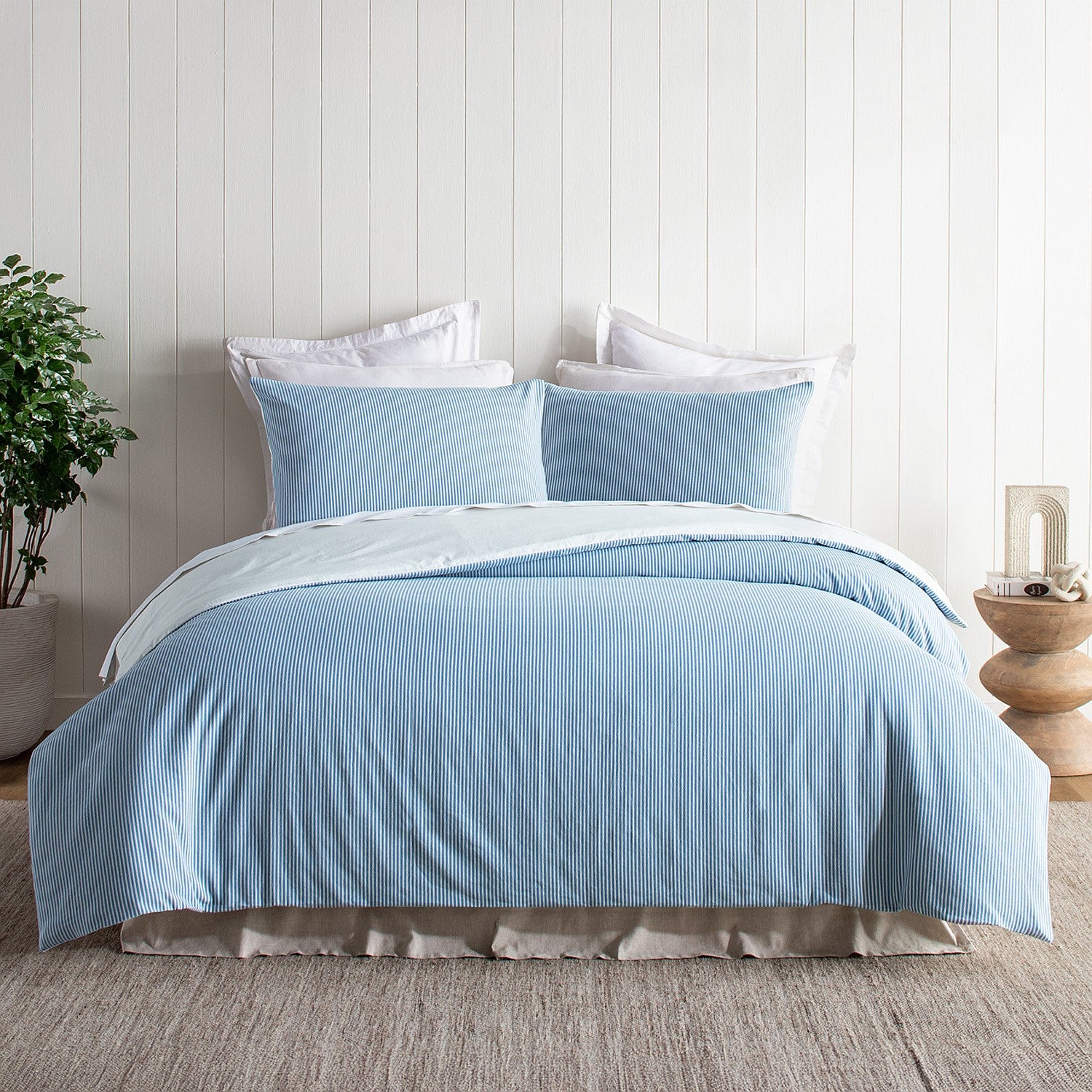 Blue textured bedding set on a bed with white pillows in a bedroom setting.