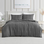 A dark gray textured duvet cover set, styled on a bed in a bright, modern bedroom with white furniture and a light gray paneled wall.