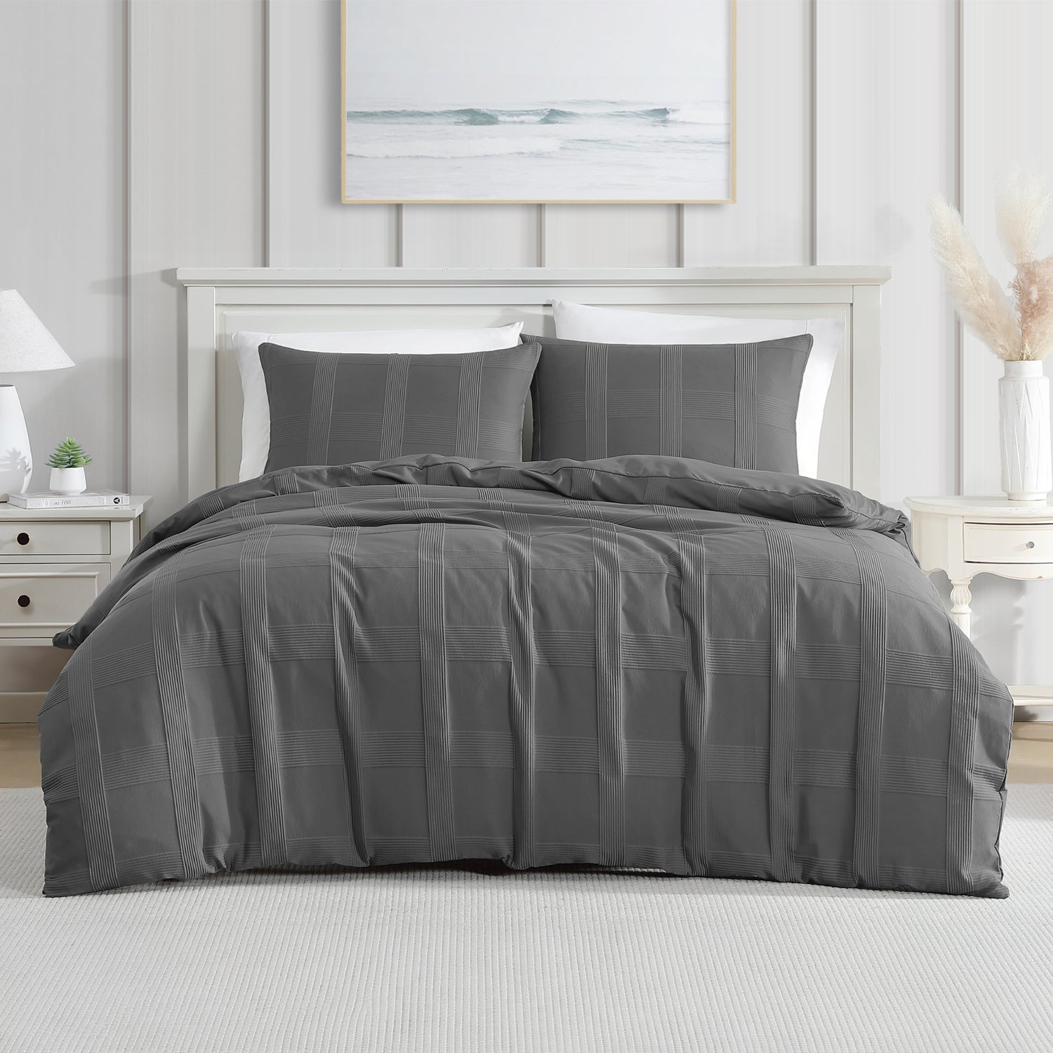 A dark gray textured duvet cover set, styled on a bed in a bright, modern bedroom with white furniture and a light gray paneled wall.