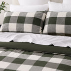 Close-up of two matching green check pillowcases with the duvet cover folded back to reveal the solid green reverse.