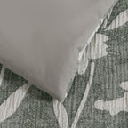 Close-up of the duvet cover showing the plain sage green reverse against the green and white floral front.