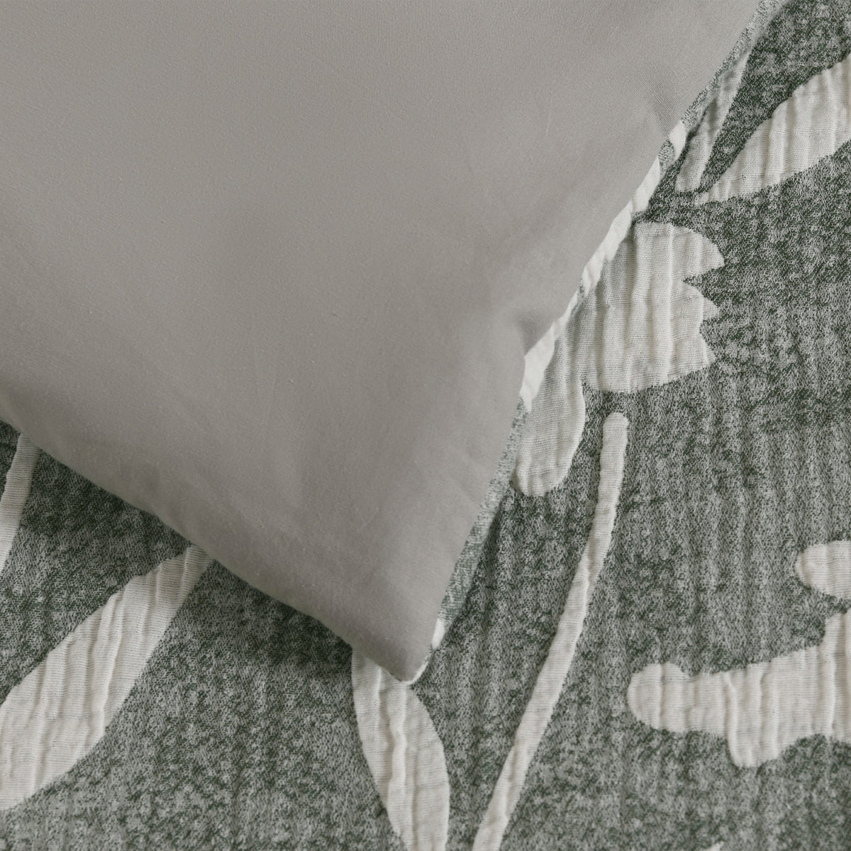 Close-up of the duvet cover showing the plain sage green reverse against the green and white floral front.