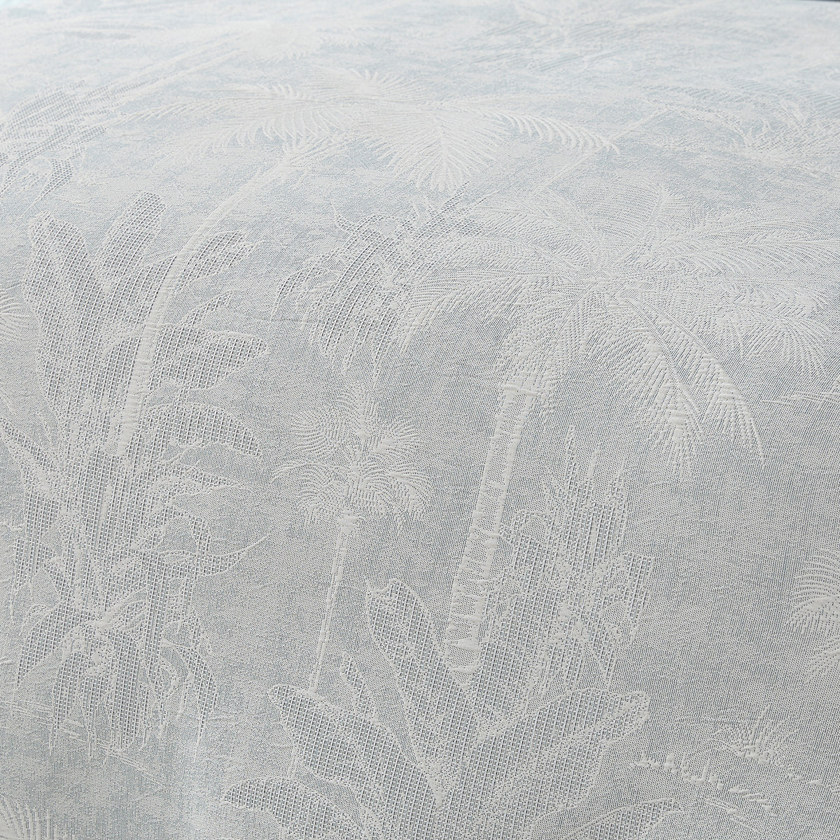 Close-Up: A close-up of the Cove Palm Toile Jacquard Duvet Cover Set in grey blue, highlighting the intricate woven palm tree design and textured fabric.