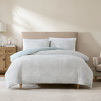 Cove Palm Toile Jacquard Duvet Cover Set in Grey Blue, featuring a subtle tropical palm tree pattern with matching pillowcases and a soft blue reverse, styled on a bed in a neutral bedroom.
