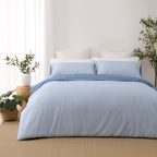 Solace Arden Reversible Duvet Cover Set shown reversed to the lighter blue side, with coordinating light blue pillowcases and a darker blue fold-over edge.