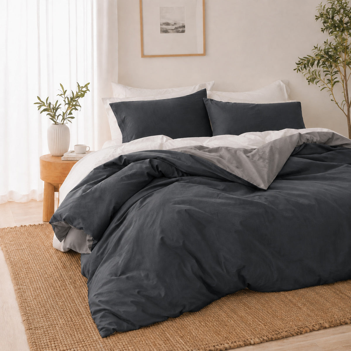 Solace Arden Reversible Duvet Cover Set styled in a charcoal and silver colourway, with charcoal bedding, a silver reverse and coordinating pillowcases in a neutral bedroom setting.