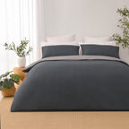 Front view of the Solace Arden Reversible Duvet Cover Set in charcoal and silver, featuring a charcoal duvet cover and pillowcases with the silver reverse folded over.