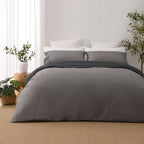 Solace Arden Reversible Duvet Cover Set shown reversed to the silver side, with coordinating silver pillowcases and a charcoal fold-over edge.