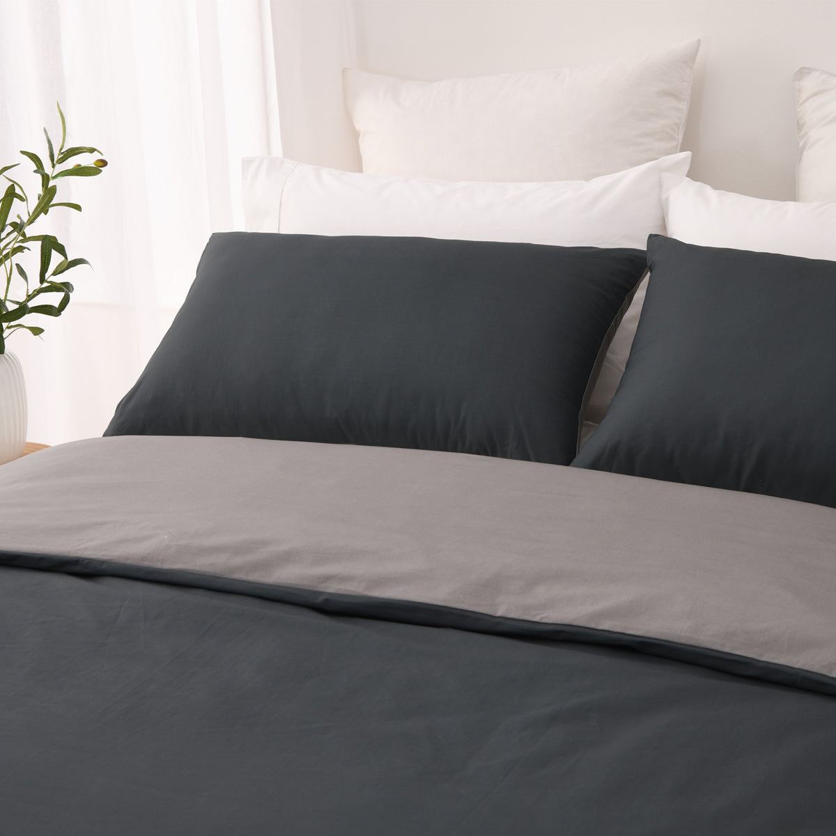 Close-up of the charcoal side of the Solace Arden Reversible Duvet Cover Set with coordinating charcoal pillowcases and the silver reverse folded over.