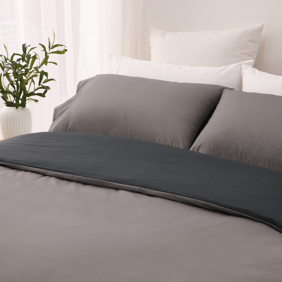 Close-up of the silver side of the Solace Arden Reversible Duvet Cover Set, featuring silver pillowcases with the charcoal reverse folded across the bed.