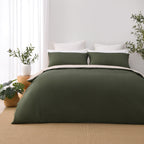 Front view of the Solace Arden Reversible Duvet Cover Set in green and natural, showing the deep green duvet cover and pillowcases with the natural reverse folded over.